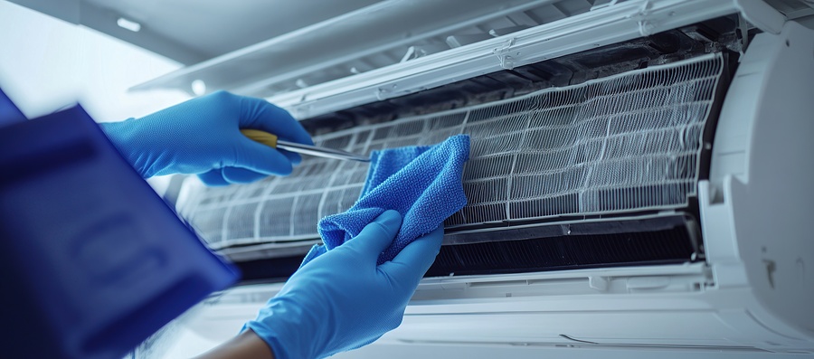 Person repairing and cleaning air conditioner filter with cloth and gloves